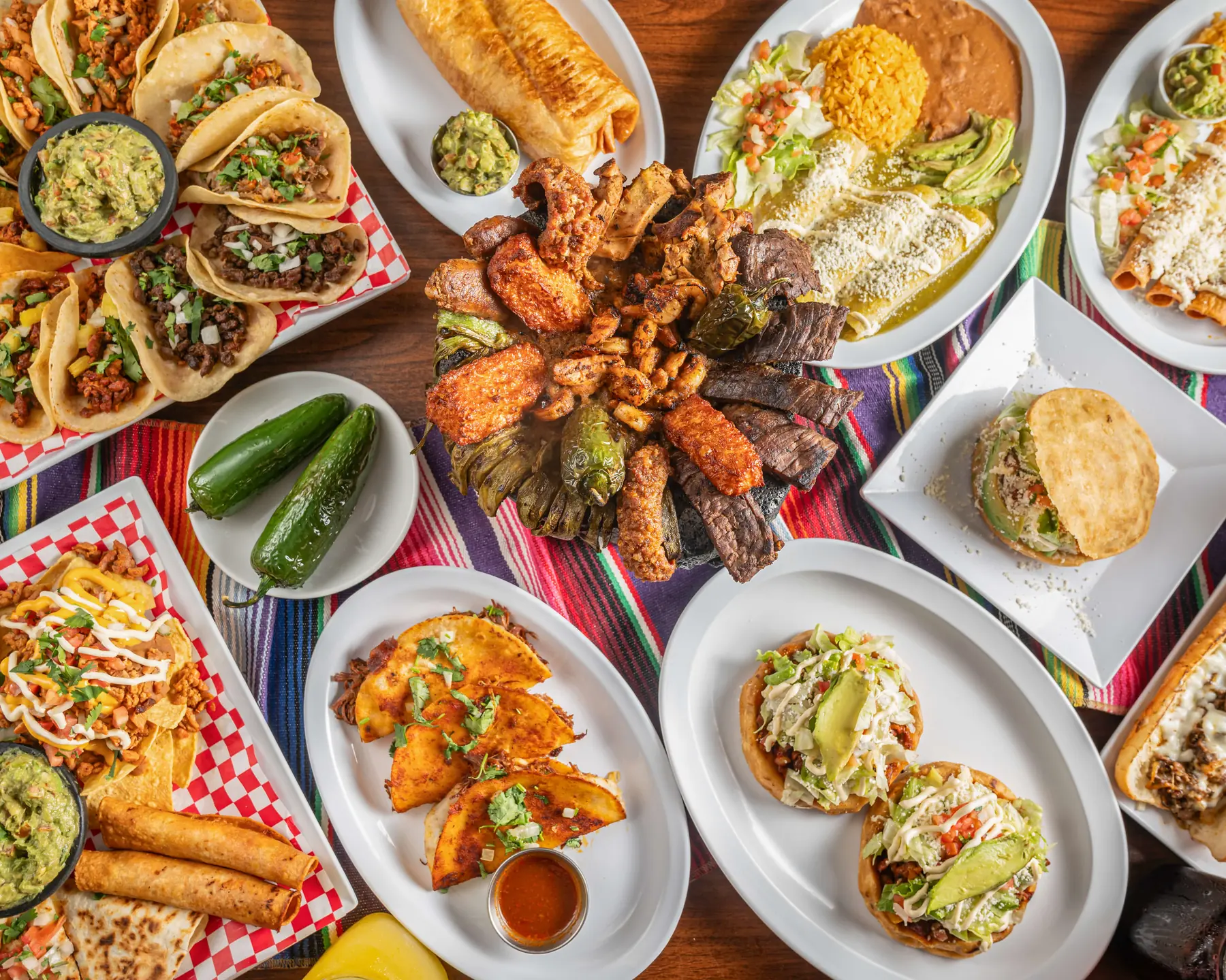 Overhead spread of tacos, guacamole, wings and appetizers prepared by Autentica Taqueria for a Miami event