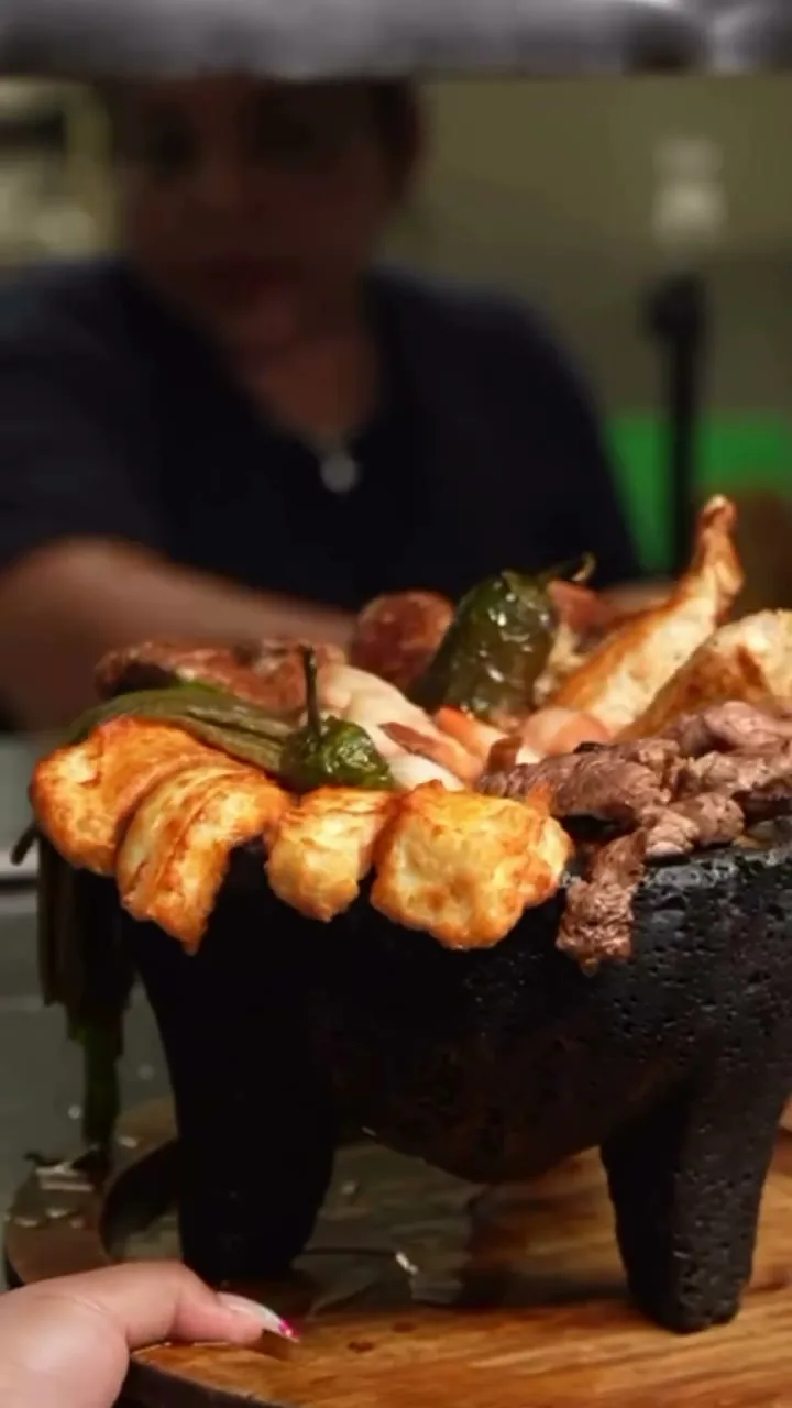 A molcajete of shrimp, steak and chiles carried to the table at Autentica Taqueria
